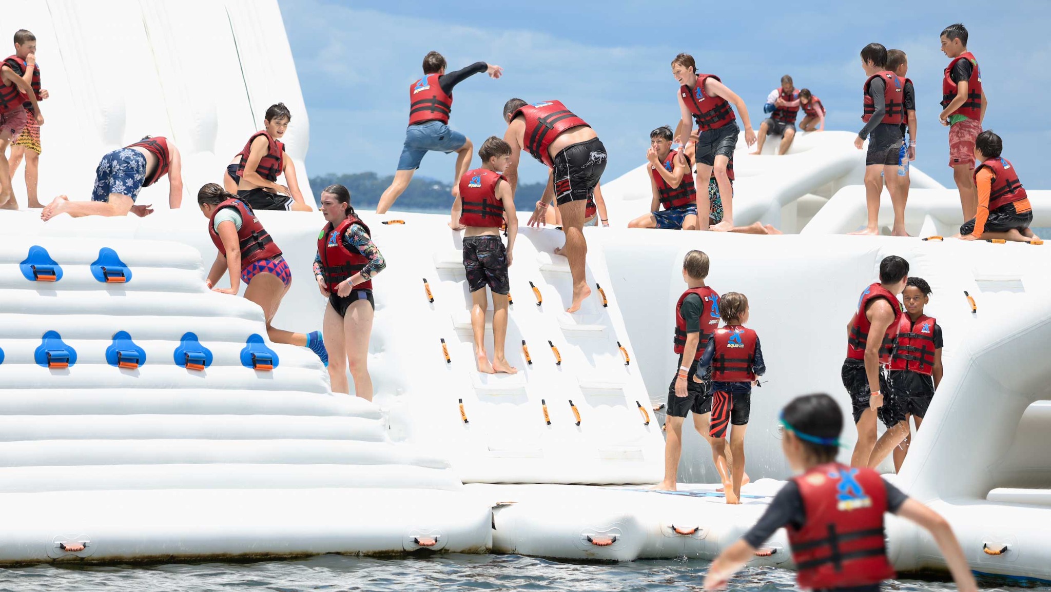 Friends tackling Aqua Warrior's floating obstacle course together at Redcliffe