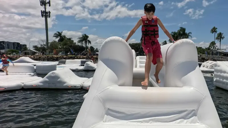 Young Aqua Warrior balancing across a white inflatable bridge