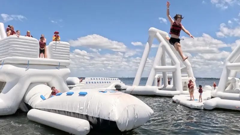 A guest leaping across the elevated Aqua Warrior course