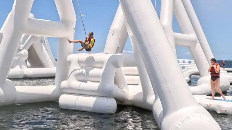 Young Aqua Warrior swinging between tall white inflatable structures